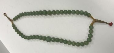 A 19th Century Chinese jade two strand bead necklace, knotted and with thread fastening,