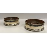 A pair of silver bottle coasters with rope-twist rims over slightly bellied sides and reeded framed