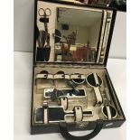 A 1920's enamel decorated travelling vanity set comprising various bottles, brushes, easel mirror,
