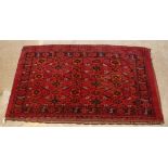 A Bokhara Juval rug, the central panel set with repeating medallions on a burgundy ground,