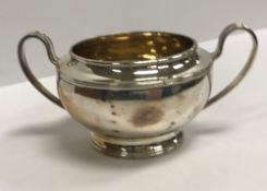 A George V silver sugar basin with gilt-washed interior flanked by open handles,