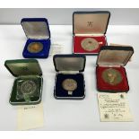 A collection of various commemorative coinage including a 25th Anniversary medallion celebrating