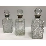 Three modern cut glass decanters with silver rims, various dates and makers and matching stoppers,