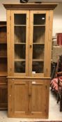 A pine freestanding corner cupboard with two glazed doors enclosing three shelves over two panel