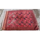 A Turkamen rug, the central panel set with repeating elephant foot style medallions on a red ground,