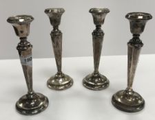 A composite set of four matching George V silver table candlesticks with beaded decoration with