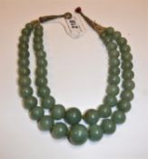 A 19th Century Chinese jade two strand bead necklace, knotted and with thread fastening,
