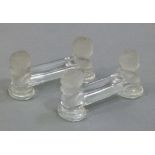 A pair of glass knife rests, the terminals with frosted glass cherub heads on disc feet, 10cm wide