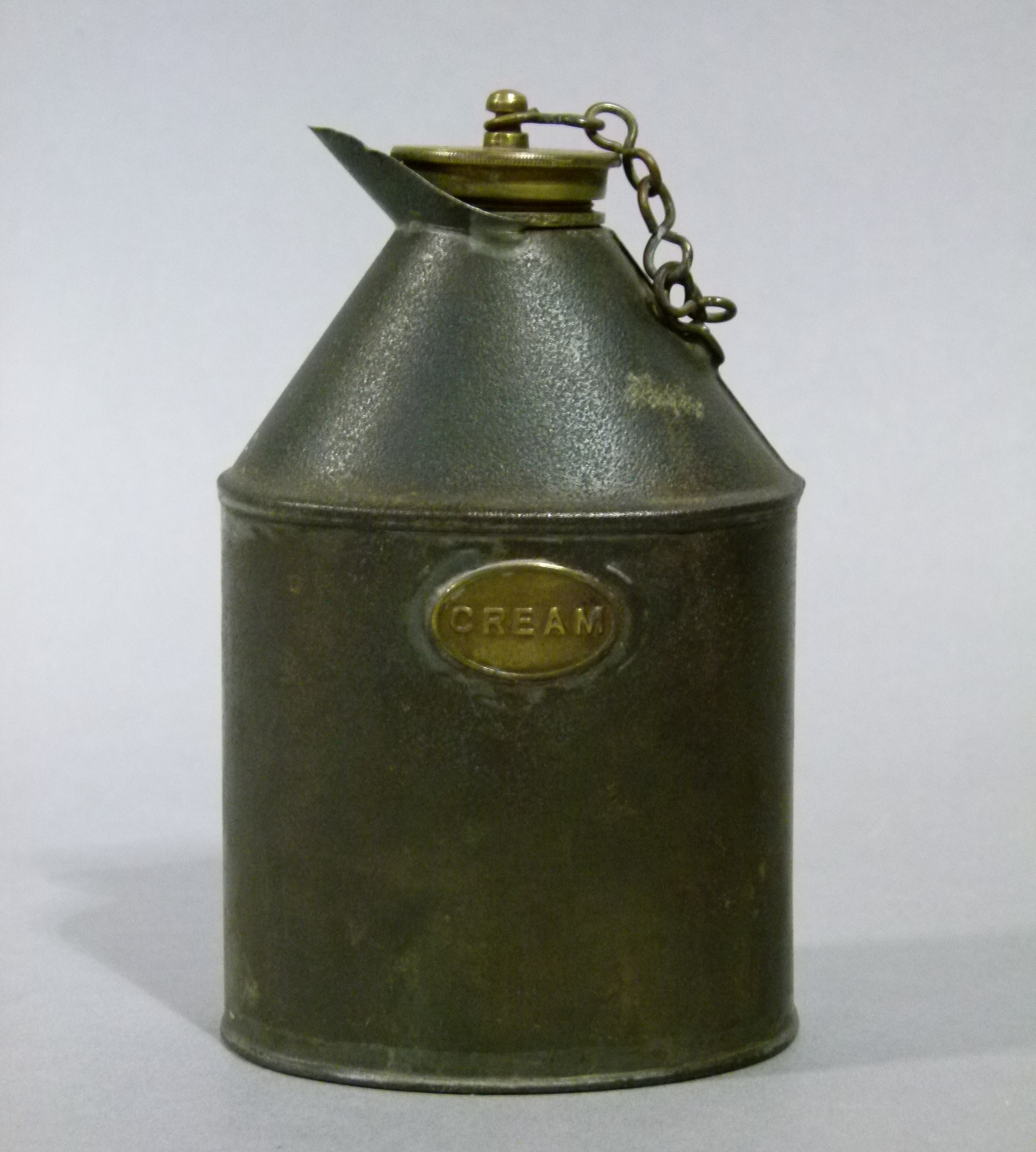 A metal cream flask with crew down brass cover the oval body applied brass label inscribed cream,