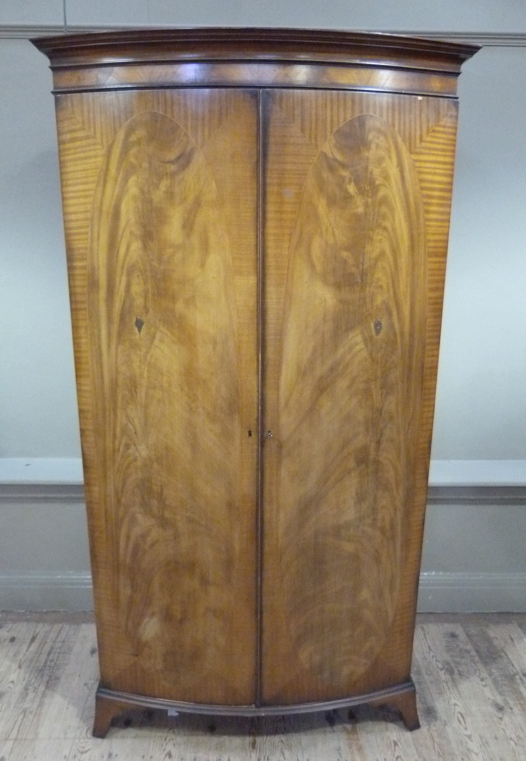 A George III style mahogany wardrobe with cavetto moulded cornice enclosed by a pair of oval figured