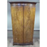 A George III style mahogany wardrobe with cavetto moulded cornice enclosed by a pair of oval figured