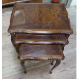 A nest of three reproduction figured walnut occasional tables of serpentine outline on foliate