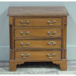 A reproduction mahogany miniature chest of four cockbeaded long drawers flanked by quarter pillars