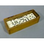 A set of ivorine and black Bakelite dominoes contained in a wooden box