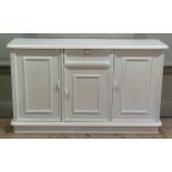 A reproduction cream painted wooden sideboard, the single drawer above a panelled door flanked by