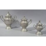 A graduated set of three Eastern lidded two handled urns, embossed overall with stylised flower