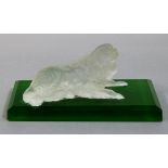 A frosted glass model of a King Charles spaniel resting on a green chamfered glass, rectangular