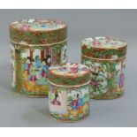 A set of three graduated Cantonese famille rose cylindrical jars and covers decorated in typical