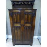 A reproduction oak cupboard with raised superstructure with flared cornice and pierced 'Gothic'