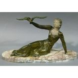An Art Deco style patinated white metal figure of a reclining woman with dove on her outstretched