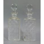 A pair of square cut glass decanters with plain chamfered angles, faceted spherical stoppers, 25.5cm