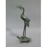 A reproduction bronze Chinese crane its mouth holding a foliate socket, it stands on a turtle