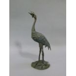A reproduction bronze small Chinese crane its mouth holding a lily pad realistically modelled and
