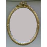 A George III style oval wall mirror with pierced ribbon tied laurel cresting, the reeded frame,