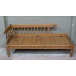 A Victorian style stained pine chaise longue with railed back, bordered seat on turned legs, 160cm