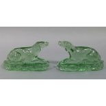 A pair of green glass flat back figures of dogs, recumbent on leaf moulded bases, 15cm wide