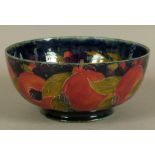 A WILLIAM MOORCROFT POMEGRANATE DESIGN FRUIT BOWL, c.1917 tubelined and glazed in ochre on a green/