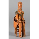 A NAIVE CARVED WOODEN FIGURE OF A SEATED MILITARY GENTLEMAN, his uniform with detail of