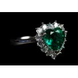 AN EMERALD AND DIAMOND CLUSTER RING in platinum the heart shaped faceted emerald claw set and raised