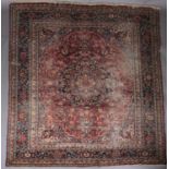 A MASHAD CARPET, North East Persia, the burgundy field with a blue floral star medallion to the