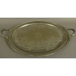 A VICTORIAN SILVER PLATED TWO HANDLED TRAY of oval outline, engraved to the centre with a coat of