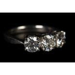 A THREE STONE DIAMOND RING in platinum, the graduated brilliant cut stones claw set in line, total
