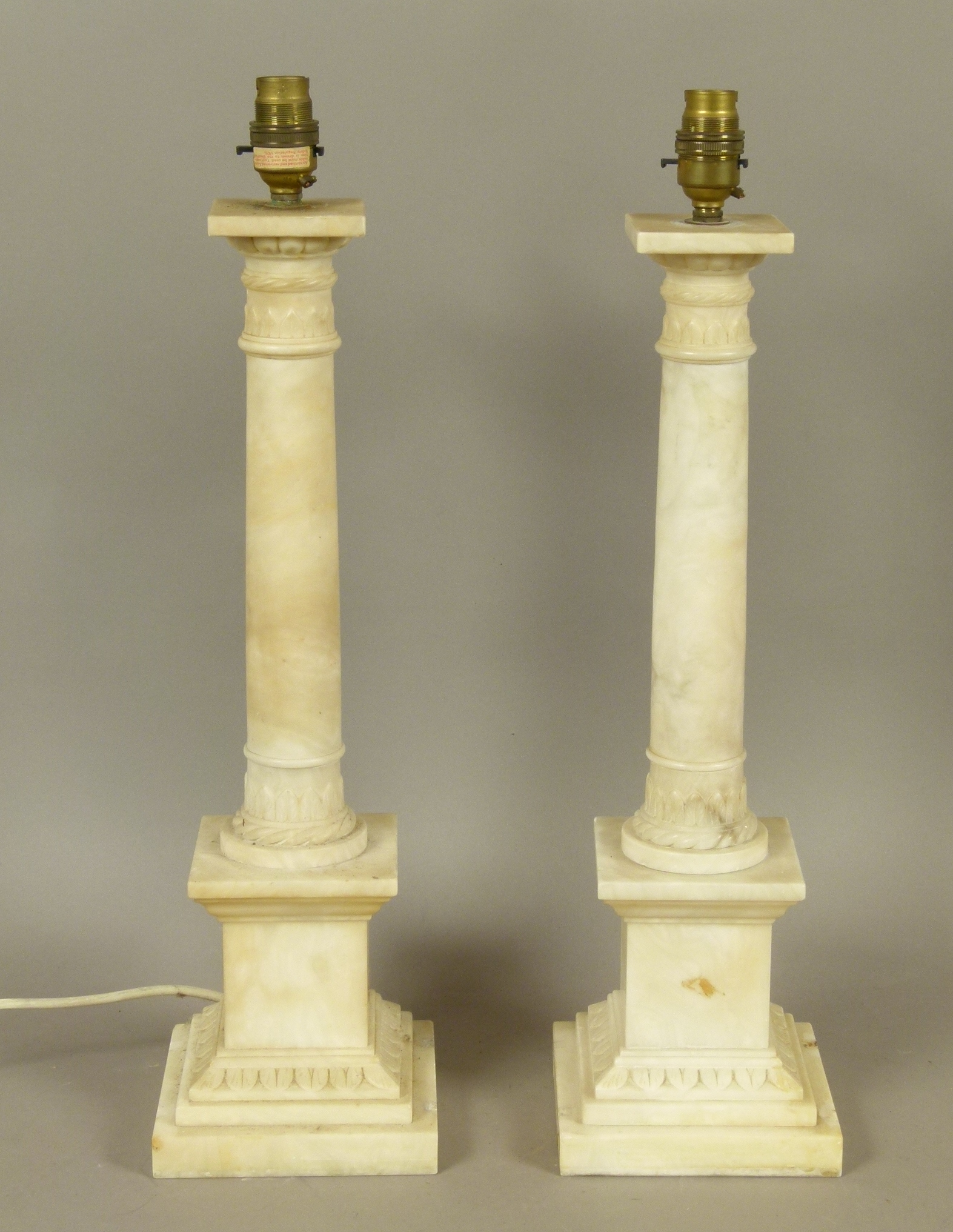 A PAIR OF ALABASTER COLUMN TABLE LAMPS with lobed and palmette carved capitals and conforming bases,