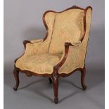 A LATE 19TH CENTURY WALNUT WINGED ARMCHAIR having a moulded encircling frame with shell cresting,