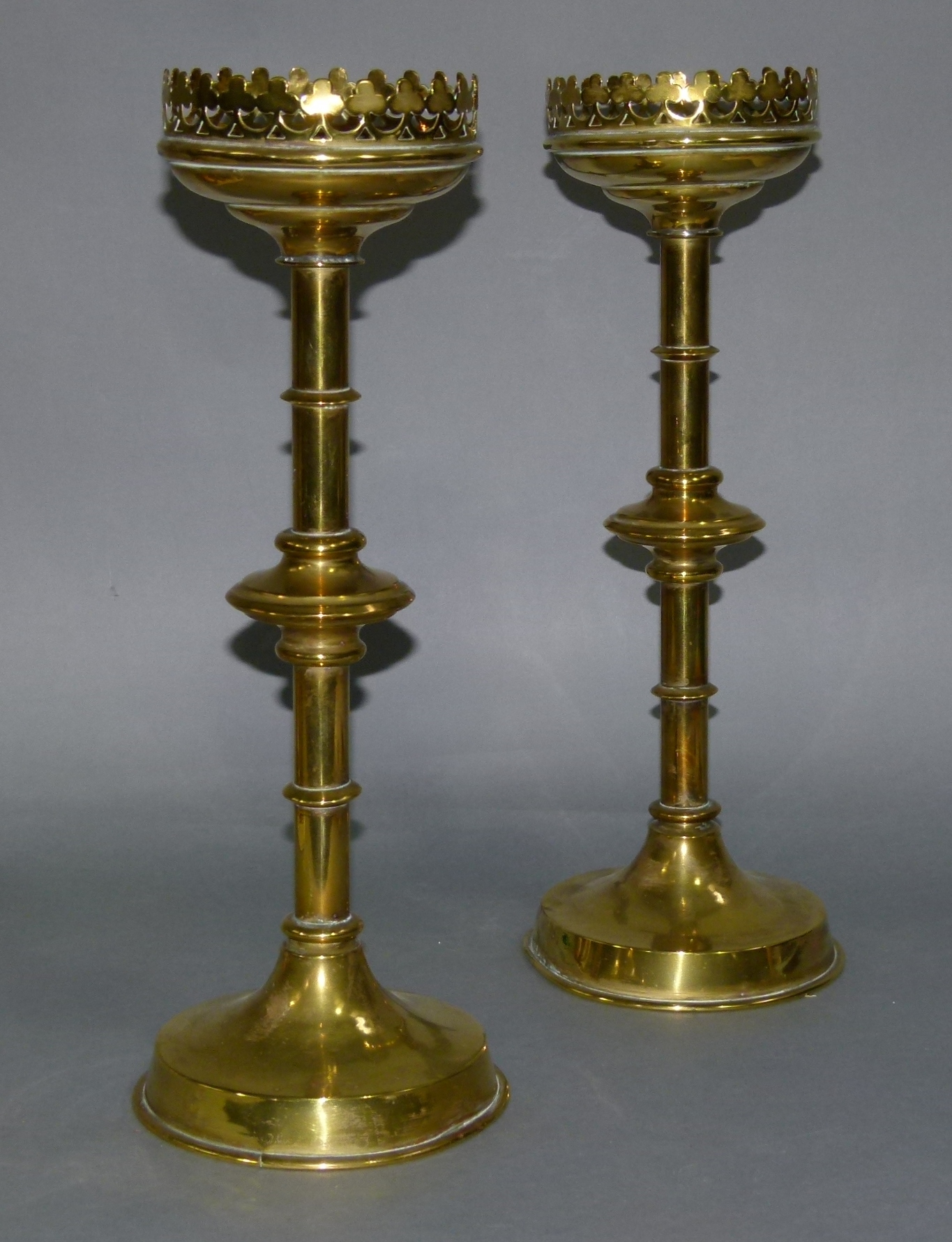 A PAIR OF 19TH CENTURY BRASS CANDLESTICKS on ring turned columns each with a bladed knop, raised