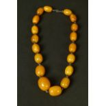 AN EARLY 20TH CENTURY AMBER NECKLACE, the graduated oval butterscotch beads joined by square section