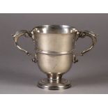 A MID 18TH CENTURY IRISH SILVER TWO HANDLED CUP of annulated urn shape, leaf capped double scroll