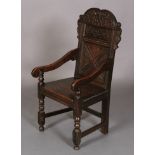 AN OAK PANEL BACK ARMCHAIR, 17th century and later, the cresting carved with scrolling foliage on