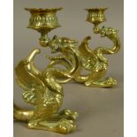A PAIR OF VICTORIAN BRASS CANDLESTICKS in the form of a dragon holding the sconce in its mouth,