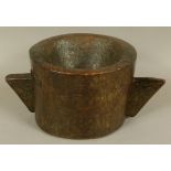 AN 18TH CENTURY TWO HANDLED WOODEN MORTAR of chip-carved cylindrical trunk form with angular