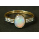 AN OPAL AND DIAMOND RING, c.1950 in 18ct gold and platinum, the oval opal cabochon collet set to the