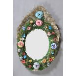 AN ORNATE VENETIAN OVAL WALL MIRROR, the convex moulded ground applied with coloured glass flowers