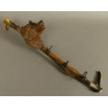 A CARVED TREEN FOX MASK MOUNTED RIDING CROP PIPE RACK with antler handle, 50cm long