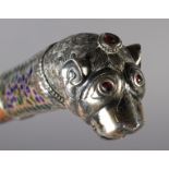 A 19TH CENTURY SILVER COLOURED METAL, ENAMEL AND GLASS WALKING STICK terminal cast as a lion's