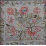 AN 18TH CENTURY NEEDLEWORK PANEL of birds amongst flowering branches within a border of trailing