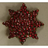 A 19TH CENTURY BOHEMIAN GARNET STAR BROOCH, the domed eight pointed star all over set with point cut